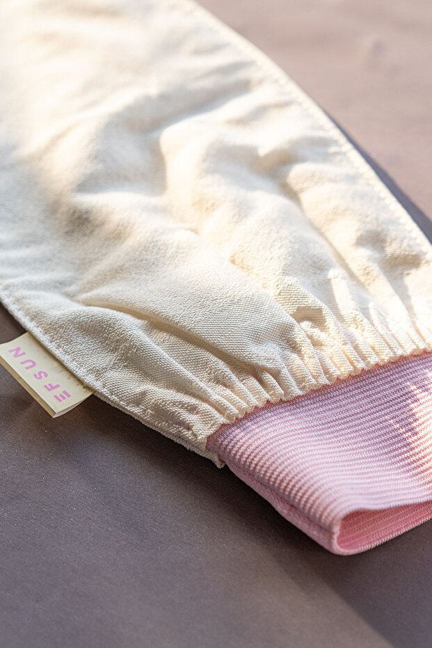 Beige bath glove with pink interior on a neutral background