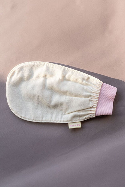 White bath mitt with pink cuff on a beige background