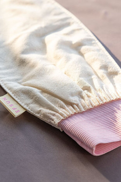 Beige bath glove with pink interior on a neutral background